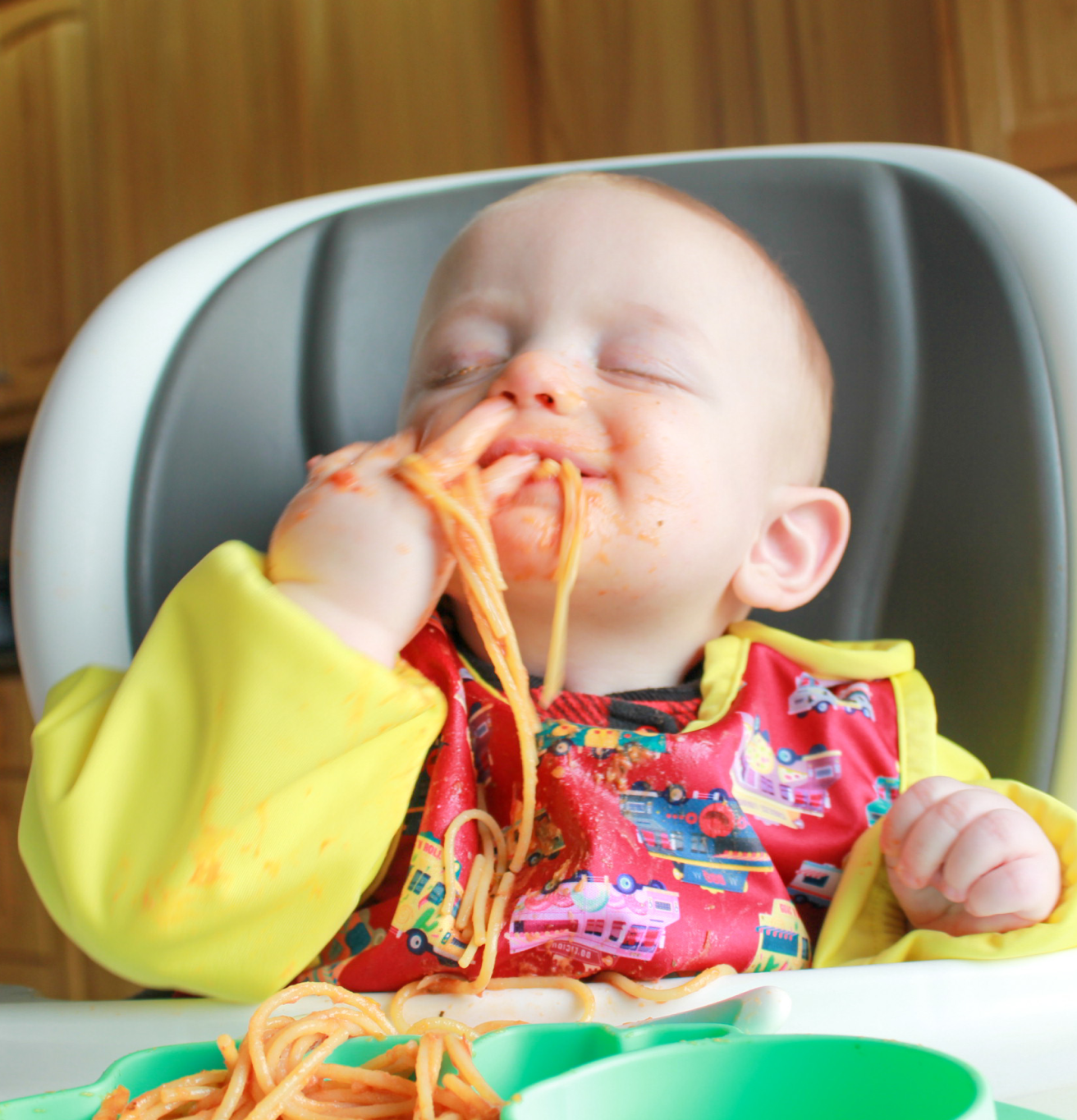 a baby eating spaghetti with a bib on